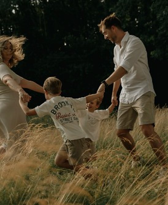 Gezin danst samen door een veld met hoog gras