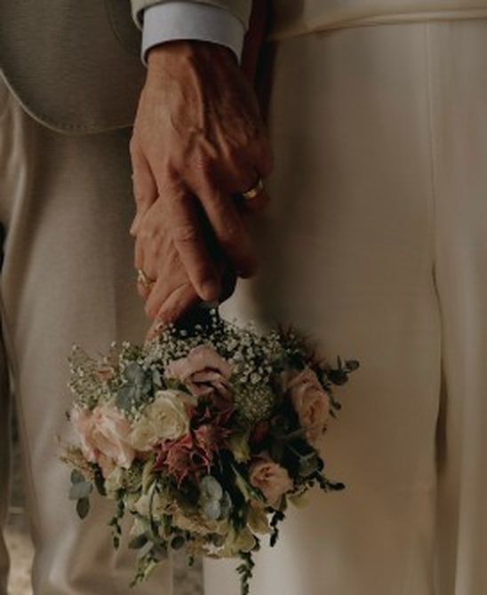 Bruidspaar hand in hand met bruidsboeket