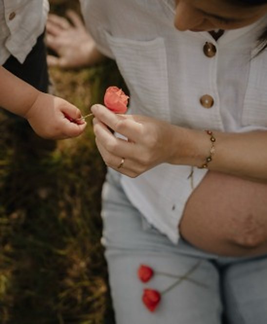 Kind geeft een bloem aan zijn zwangere mama