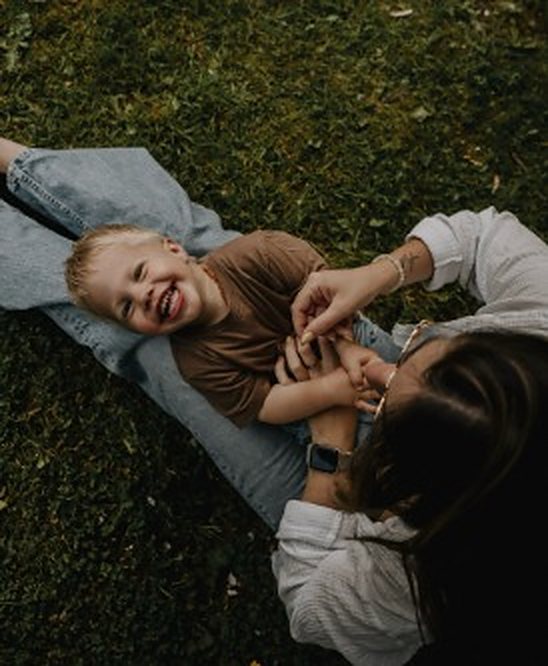 Mama en zoon liggen lachend in het gras