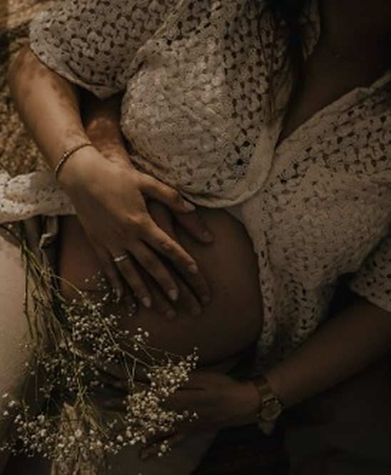 Handen op een zwangere buik met droogbloemen